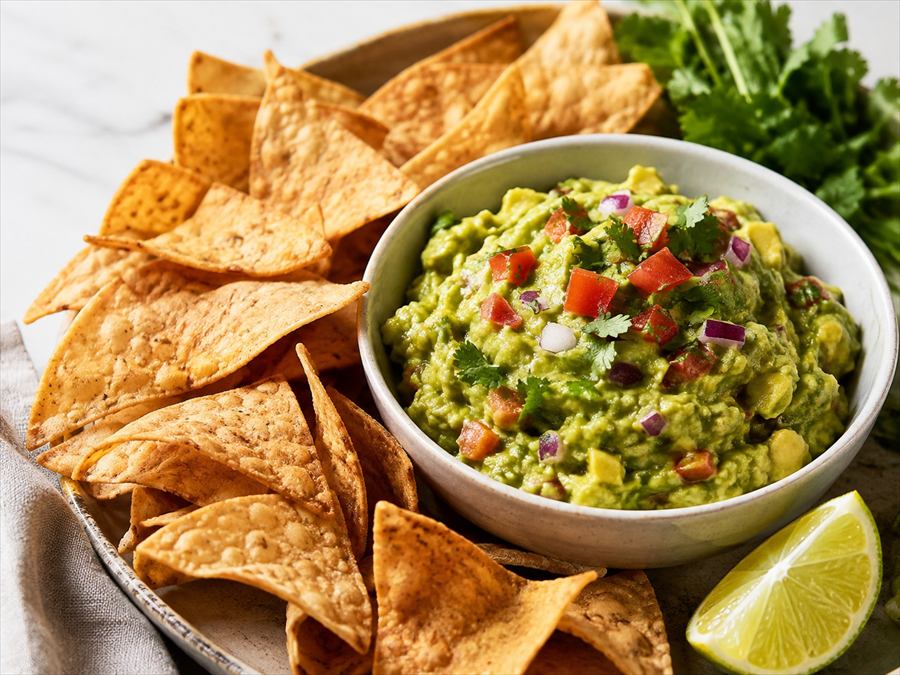 Bol de guacamole con tomate y cilantro, acompañado de nachos